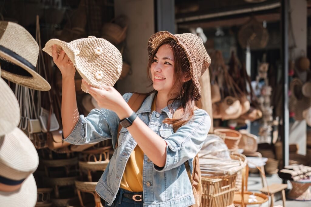 Asian tourist girl shopping, walking in famous local street market looking at beautiful straw hats